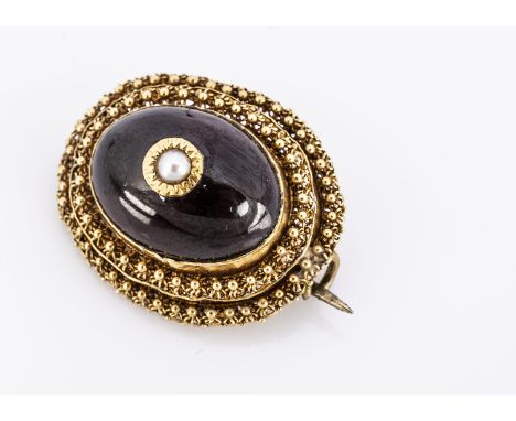 An early 19th century oval garnet brooch, cabochon, with centre setting of a seed pearl, with in a double filigree band, 2.8 