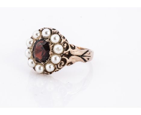 An 9ct gold antique style garnet and seed pearl cluster ring, central mixed oval cut garnet surrounded by half cut pearls, ri