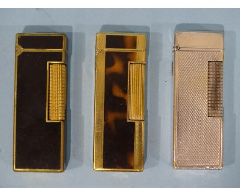 A Dunhill slim silver-plated engine-turned lighter, a Dunhill gold-plated and mottled brown slim lighter and one other, each 