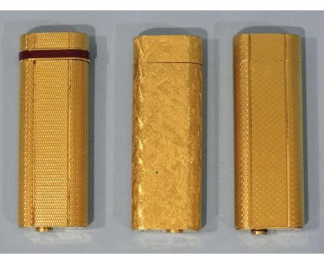 A Cartier engine-turned gilt metal cigarette lighter with red band around the flip lid, serial no.290842P, another Cartier en