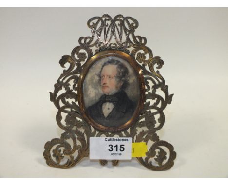 A GEORGIAN PORTRAIT MINIATURE OF A GENTLEMAN IN FORMAL ATTIRE IN PIERCED ORNATE EASEL BACKED BRASS FRAME