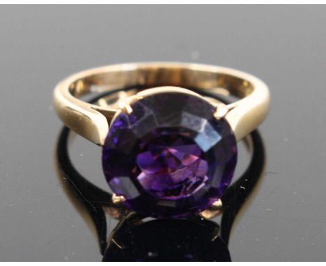 A yellow metal and purple paste set solitaire ring, stamped 18k but tests as approx 14/15ct gold, size K, 4g