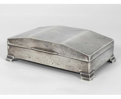 An Art Deco silver table cigarette box, of sloped rectangular form, the hinged cover with engine turned decoration and rectan