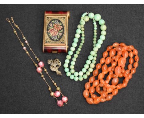 A vintage biscuit tin containing a small selection of costume jewellery including graduated carnelian beads, pink glass and y