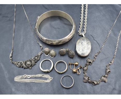 An assortment of silver and white metal jewellery, including a large hinged bangle with decorative foliage engraving and safe