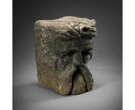 A CARVED STONE CORBEL HEAD  14TH/15TH CENTURY  Dark hardstone male face- projecting scrolling hairline above moustachioed fac