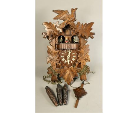 A mid Century Swiss musical cuckoo clock with carved wood decoration, leaf shaped pendulum and three cone shaped weights. 