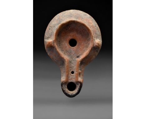 Ca. 100-200 ADA terracotta oil lamp with a globular body with a deep, channeled spout with a vent hole and flaring finial. Ci