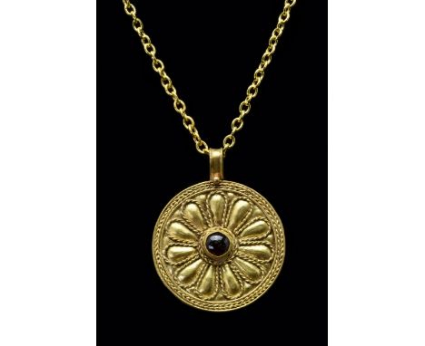 Ca. 100-300 ADA flat, disc-shaped pendant with a braided frame and a central floral motif. Each petal is formed of a repoussé