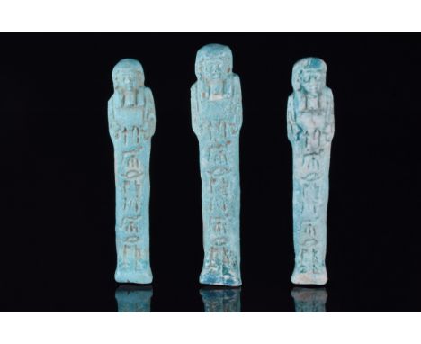 Ca. 664–332 BCA set of three finely modelled blue-glazed faience shabti figures in mummiform pose. Wearing a lappet wig and f