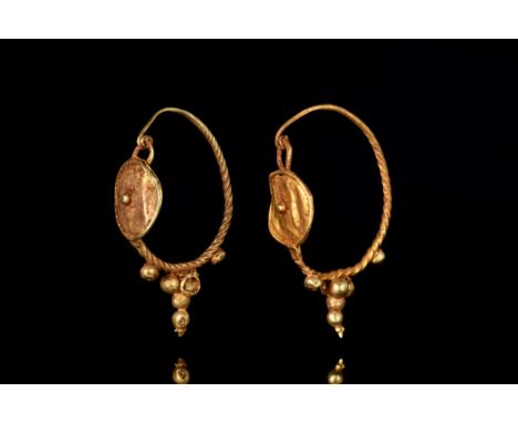 Ca. 100-200 ADA matched pair of gold earrings, each with a shield centered by a large granule and framed by twisted wire, joi