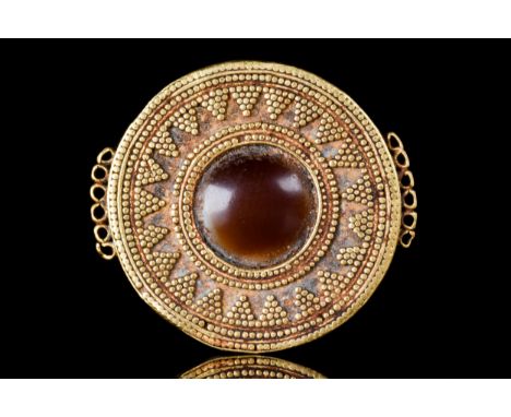 Ca. 400 BCA finely rendered gold disc-shaped pendant, hammered from thin gold, with an agate eye to the center, along the bro