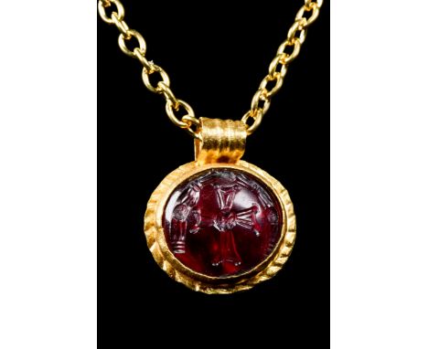 Ca. 600-700 ADA gold disk-shaped pendant with a suspension loop and a flounce border framing a cell set with a garnet stone e