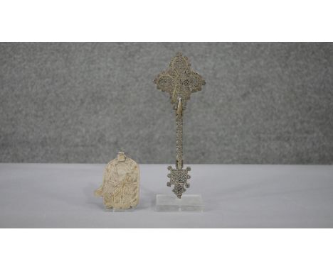 An Ethiopian silver plate Coptic pierced design hand cross on clear display stand along with a silver plated engraved Hamsa. 