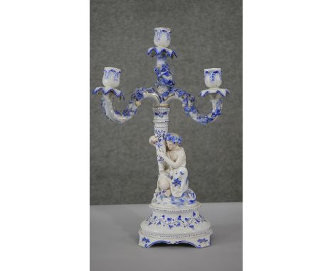 A 19th century hand painted porcelain three branch candelabra. The base modelled as a crouching female, with relief floral de