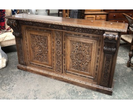 A well carved 19th century oak sideboard/buffet, the moulded top over a frieze carved with grapes, flowers and scrolling acan