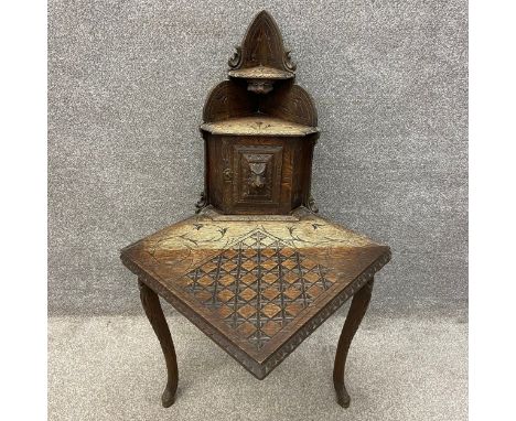 A late 19th century oak corner table having a shaped and stepped waterfall superstructure of two small shelves above a canted