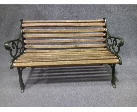 A contemporary painted cast iron garden bench in the 19th century style with scrolling openwork decoration and teak slats. W.