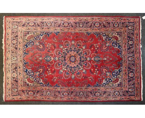 A Sarouk carpet,decorated with a central blue medallion to a red field and navy border,205cm x 195cmLosses to the tassels. So