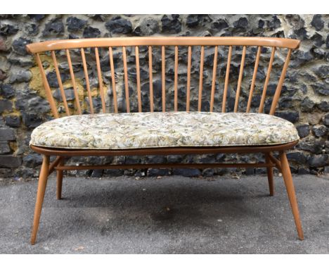 A mid century elm and beechwood Ercol loveseat, with cushion, spindle back, raised on tapered turned legs, joined by a turned