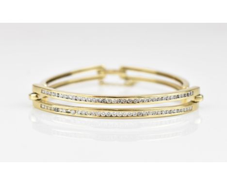 An 18ct yellow gold and diamond bangle, set with two interspersed rows of channel set brilliant cut diamonds, on pierced link