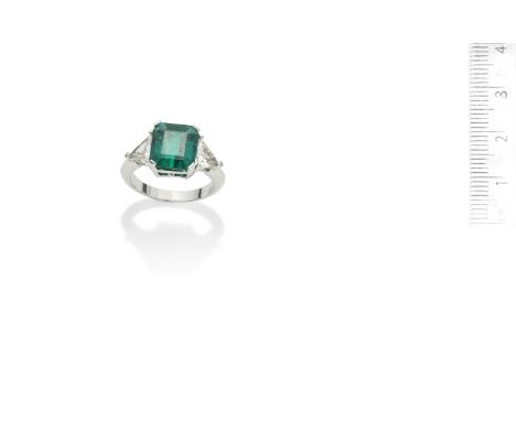 An emerald and diamond ringThe step-cut emerald, weighing 3.94 carats, between triangular-cut diamond shoulders,  diamonds ap