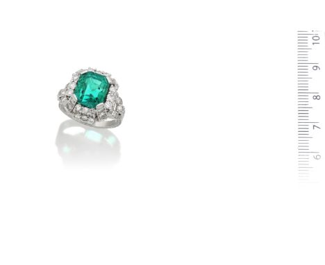 An emerald and diamond ringThe step-cut emerald within a raised geometric mount set with brilliant-cut diamonds, the hoop wit