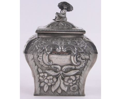 A George IV Irish silver tea caddy,surmounted by a figure under a parasol, with relief chased and embossed ogee sides, engrav