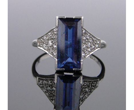 An 18ct white gold rectangular-cut sapphire ring circa 1910,diamond set shoulders, sapphire 11mm x 5mm, size M.