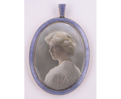 An unmarked gold and blue enamel framed pendant,containing a hand coloured photographic portrait of a woman, height excluding