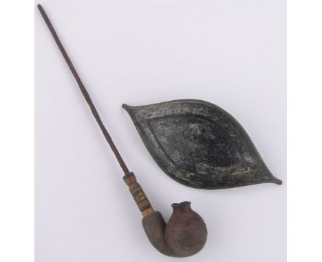 A Papua New Guinea tribal terracotta pipe,with wood and metal stem, together with an Oriental 19th century brass and enamel b
