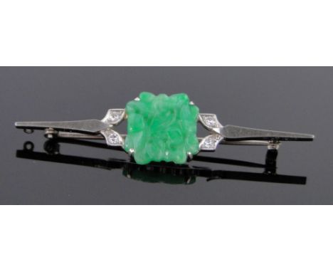 An 18ct white gold bar brooch with a central carved and pierced jade panel flanked by diamonds,length 50mm.