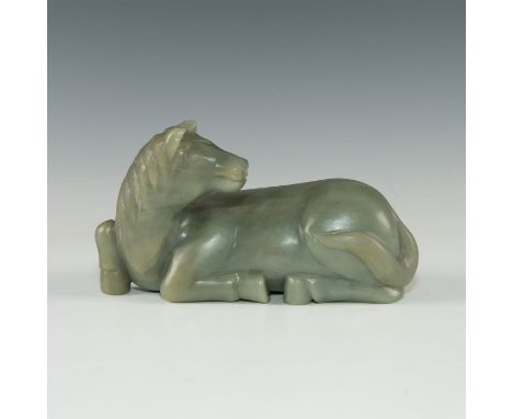 Dark inclusions.Carved from a single piece of jade, depicting a recumbent horse, its head angled to one side. Issued: Attribu