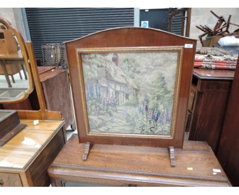 A vintage stained frame fire screen having woolwork inset