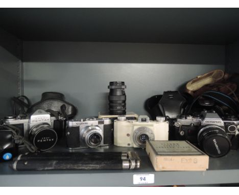 A selection of cameras including a Pentax, a Voigtlander Vito B, an Ilford Advocate an Olympus OM10 and a Praktica B100, with