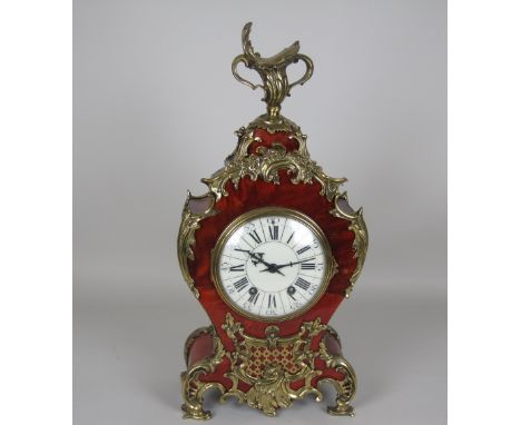 A Louis XV style Mantel Clock having cream dial, 8-day movement in tortoiseshell case with ormolu scroll mounts and two handl