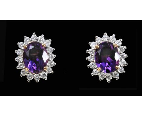 A pair of Amethyst and Diamond Cluster Earrings each claw-set oval-cut amethyst within frame of sixteen brilliant-cut diamond