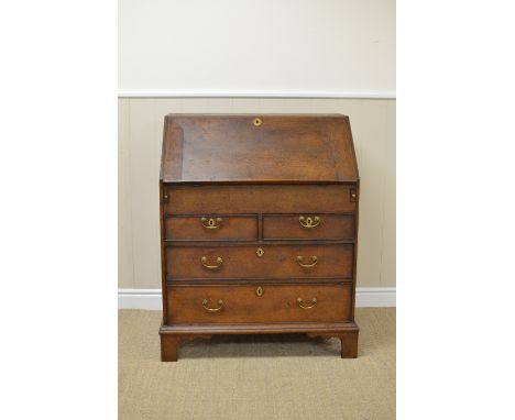 A Georgian oak small Bureau with interior pigeon holes, drawers, door and well, two short and two long drawers beneath on bra