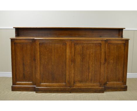 A 19th Century oak Breakfront Cabinet with low raised shelf above two pairs of solid panelled doors on plinth base, 6ft 6in