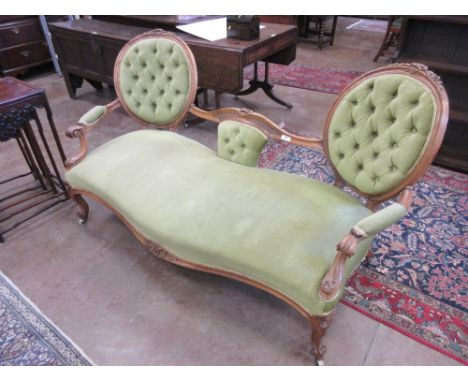 A Victorian walnut framed double spoonback Sofa with carved floral decoration and green button back upholstery on carved fron