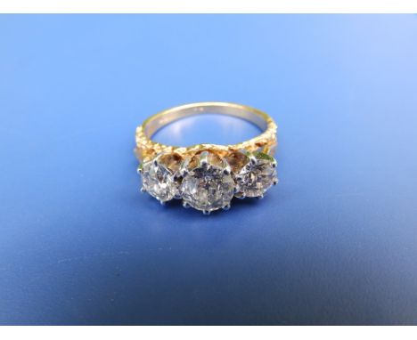 A three stone diamond ring, the central old cut diamond weighing approximately one carat raised in high claws flanked by two 