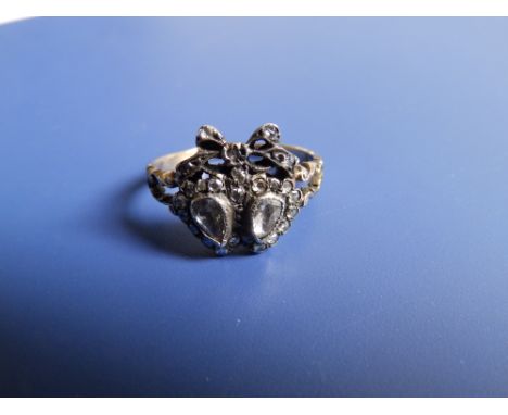 A Victorian diamond set ring designed as two hearts beneath a tied ribbon. Finger size O/P.