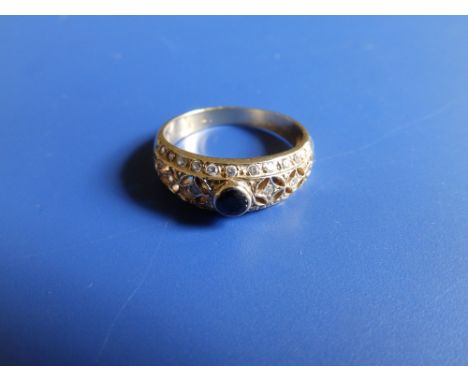 An openwork band ring set with a dark sapphire and small diamonds.  Finger size  O.