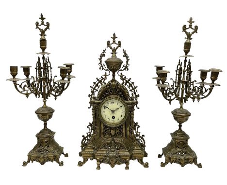 A late 19th century profusely decorated brass cased timepiece mantle clock with two matching five light candelabra, break fro