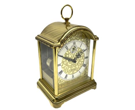 A 20th century brass cased Kieninger (German) chiming mantle clock with a break arch top and three glazed panels, polished sh