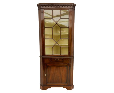 George III mahogany floor standing corner display cabinet, dentil cornice, upper astragal glazed door above small drawer and 