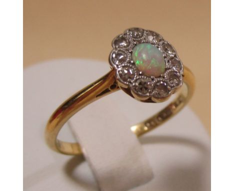 An opal and diamond cluster ring, the central oval opal cabochon surrounded by small round diamonds in a milligrain mount, al