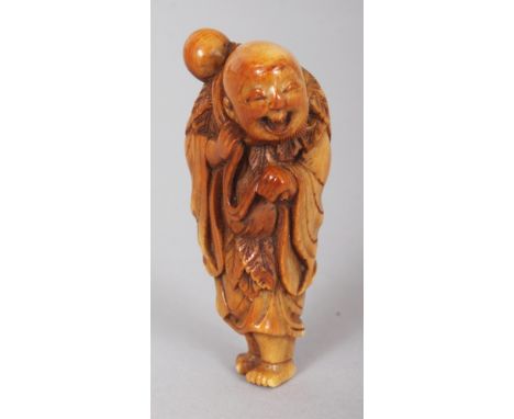 A JAPANESE EDO/MEIJI PERIOD STAINED IVORY NETSUKE OF A STANDING SENNIN, with cheerful expression and bearing a gourd on his s