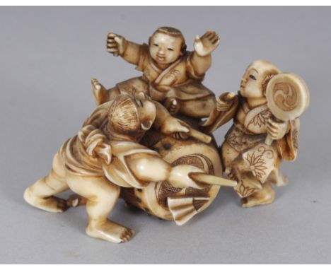 A GOOD QUALITY SIGNED JAPANESE MEIJI PERIOD STAINED IVORY OKIMONO OF THREE BOYS PLAYING AROUND A LARGE DRUM, the underside wi