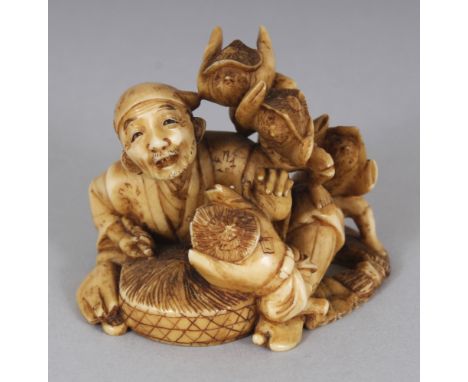 A SIGNED JAPANESE MEIJI PERIOD STAINED IVORY NETSUKE OF A SEATED MAN IN THE COMPANY OF FOUR TENGU, the base with an engraved 